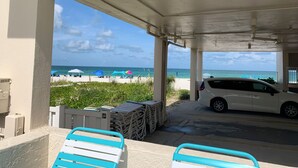 A covered outdoor area with a view of the beach, a white car, and stacked chairs. - Gulf side! No crossing the street to get to the beach! COQUINA BEACH CLUB 109 (Bradenton Beach)