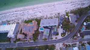 Vue aérienne d’une zone côtière comprenant une plage, un club de plage appelé Coquina Beach Club et divers bâtiments.