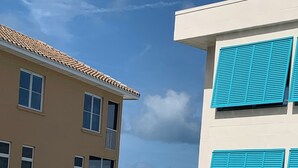 A pool area with a view of the ocean, a building with blue shutters, and a white fence. - Gulf side! No crossing the street to get to the beach! COQUINA BEACH CLUB 109 (Bradenton Beach)