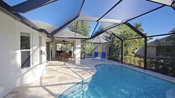Une piscine couverte avec un espace patio, un ventilateur de plafond et une vue sur le paysage environnant.