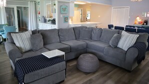 A modern living room with a sectional sofa, ottoman, and a small table.
