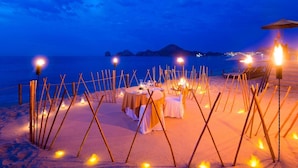 A beach dinner setup with tables and chairs, surrounded by candles and a view of the sea and mountains. - Villa La Estancia Resort-Medano Beach GORGEOUS, LUXURY 2 bd+3 bath private villa (Cabo San Lucas)