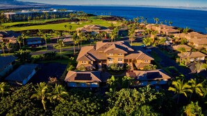 A coastal resort with multiple bungalow-style buildings, a golf course, and a view of the ocean.