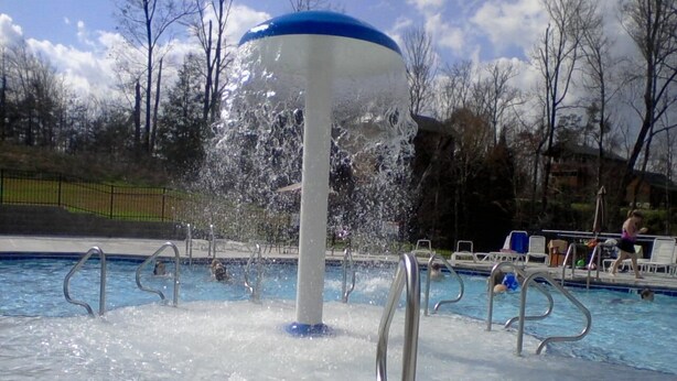 Una piscina con una fuente, rodeada por una terraza con barandillas de metal.