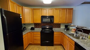 Una cocina con armarios de madera, un refrigerador negro, un microondas, una estufa y un lavavajillas.