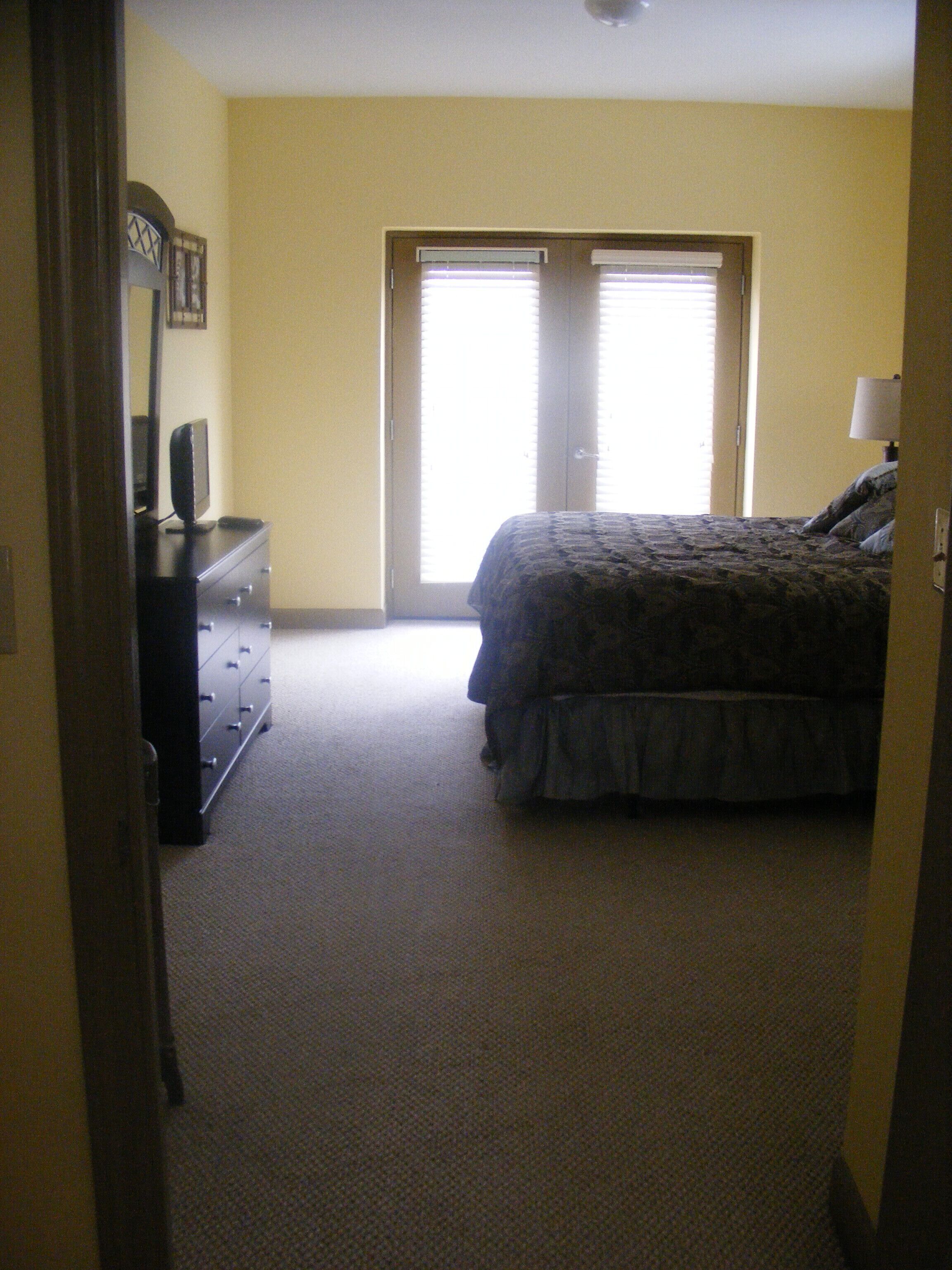 A bedroom with a bed, dresser, and a television on a dresser.