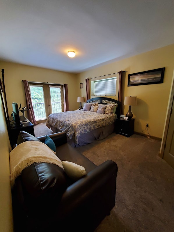 A bedroom with a bed, a sofa, a desk, and a window.