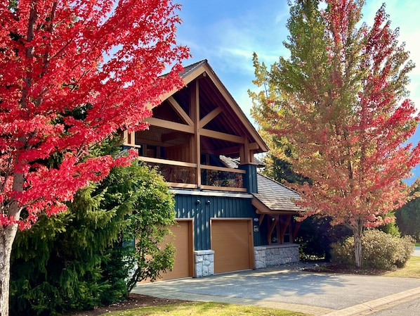A two-story house with a prominent wooden structure, a large garage, and a well-maintained front yard with trees.