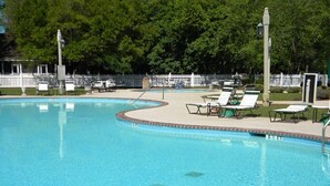 A swimming pool with lounge chairs and a white picket fence in the background. - 'Beneath The Branches' Cottage Steps to Golf and Tennis. Pet-Friendly! (Murrells Inlet)