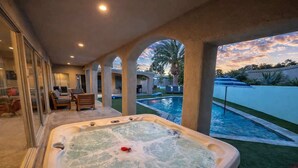 Un jacuzzi con vistas a una piscina y palmeras.