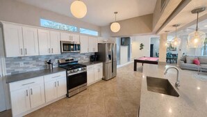 Una cocina moderna con armarios blancos, electrodomésticos de acero inoxidable y una isla central con fregadero.