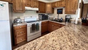 Una cocina con armarios de madera, una estufa blanca, un microondas y una cafetera.
