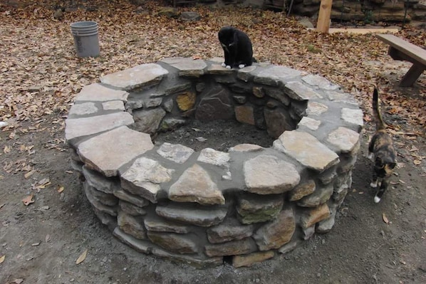 A stone fire pit with a cat sitting on top.