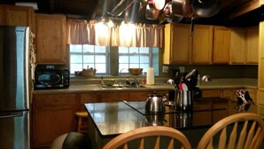 Una cocina con armarios de madera, microondas, fregadero y estufa.