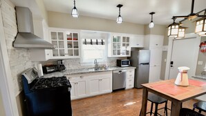 Une cuisine avec des meubles blancs, une cuisinière, un four à micro-ondes et un réfrigérateur.