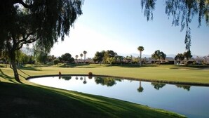 A golf course with a pond, palm trees, and houses in the background. - Pond View Villa @ Desert Princess Country Club & Golf Resort (Cathedral City)