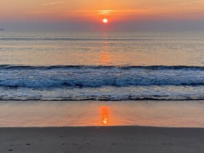 Ein Sonnenuntergang über dem Meer mit Wellen am Ufer.