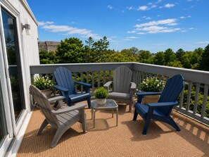 Een terras met Adirondack stoelen, een kleine tafel en potplanten.