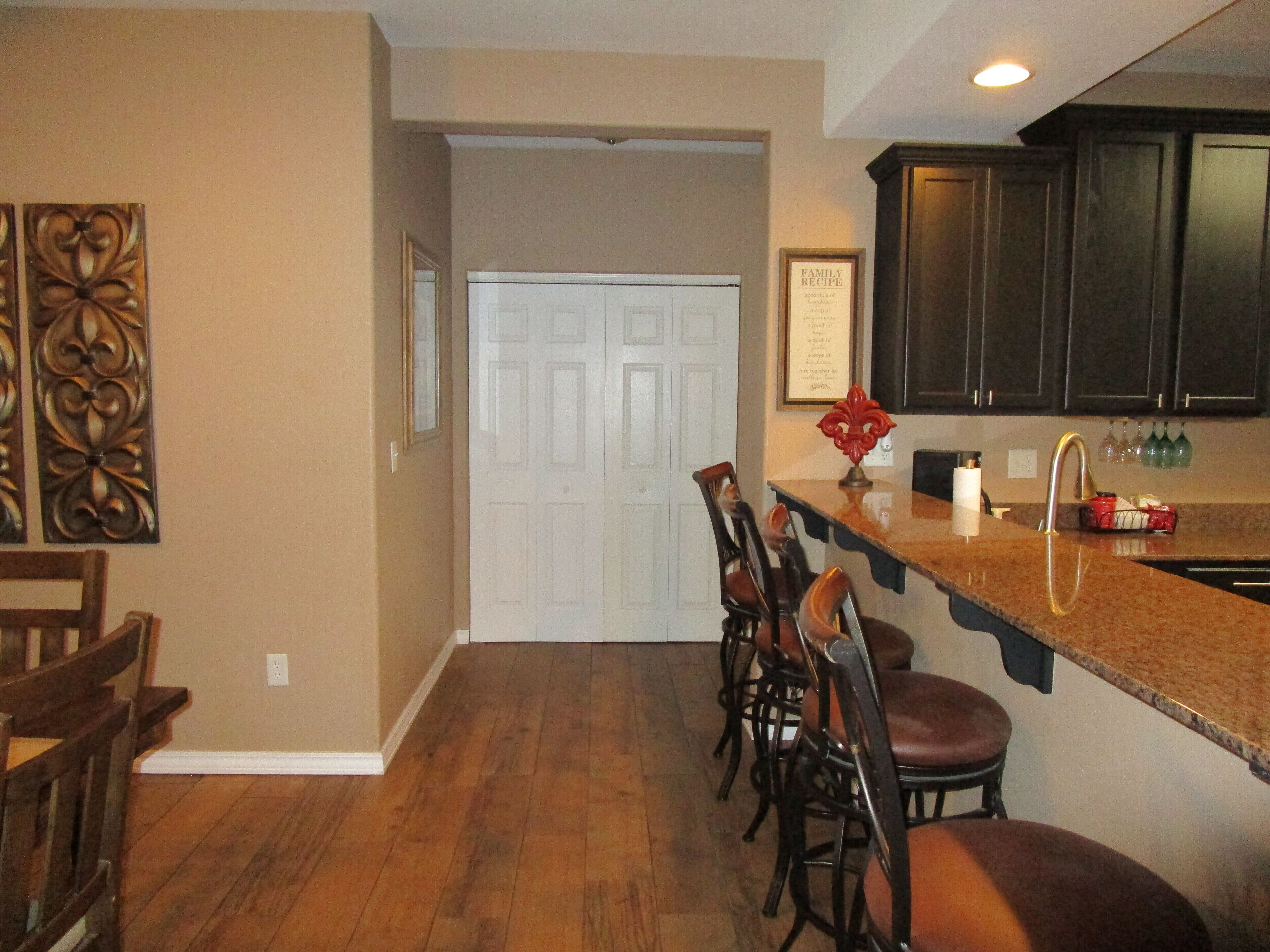 A kitchen with dark wooden cabinets, a granite countertop, and a white door.