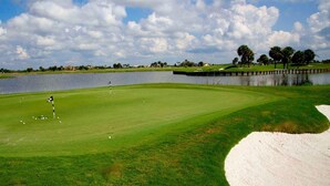 Un campo de golf con un obstáculo acuático, búnkeres de arena y un palillo de señales.