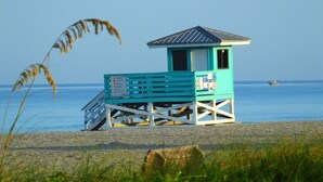 Una torre de salvavidas en la playa con techo inclinado y un cartel.