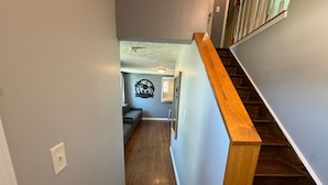A narrow hallway with wooden stairs leading to a room.