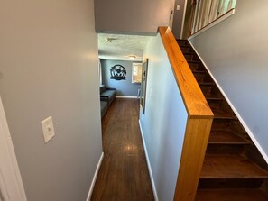 A narrow hallway with wooden stairs leading to a room.