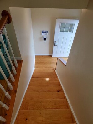 A wooden staircase leading to a white door with a notice sign on the wall.