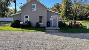 A single-story house with a front porch, a small attached garage, and a gravel driveway.