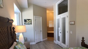 A bedroom with a bed, a nightstand, a lamp, a door, and a window. - Luxury End-Unit Townhome: Private Elevator, Rooftop Hot Tub & Gulf Views (Clearwater)