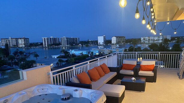 A rooftop patio with a hot tub, outdoor seating, and string lights. - Luxury End-Unit Townhome: Private Elevator, Rooftop Hot Tub & Gulf Views (Clearwater)