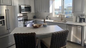 A modern kitchen with stainless steel appliances, white cabinetry, a large window, and a view of the city. - Luxury End-Unit Townhome: Private Elevator, Rooftop Hot Tub & Gulf Views (Clearwater)