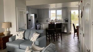 A modern kitchen with white cabinets, stainless steel appliances, and a view of the city. - Luxury End-Unit Townhome: Private Elevator, Rooftop Hot Tub & Gulf Views (Clearwater)