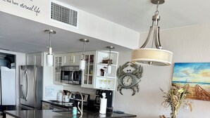 Une cuisine moderne avec un îlot central, une table à manger en bois avec des chaises, et un tapis au style rustique.