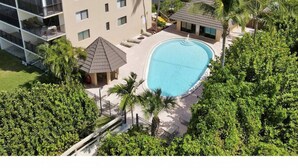 Un hôtel doté d’une piscine entourée de palmiers et d’un immeuble à plusieurs étages avec des balcons.