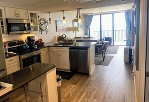 A modern kitchen with stainless steel appliances, a dining area with a view, and a spacious living area. - Beachfront 2BR, 2BA directly on beach 15th-Floor SunsetsOnbalcony Pool & Hot Tub (Marco Island)