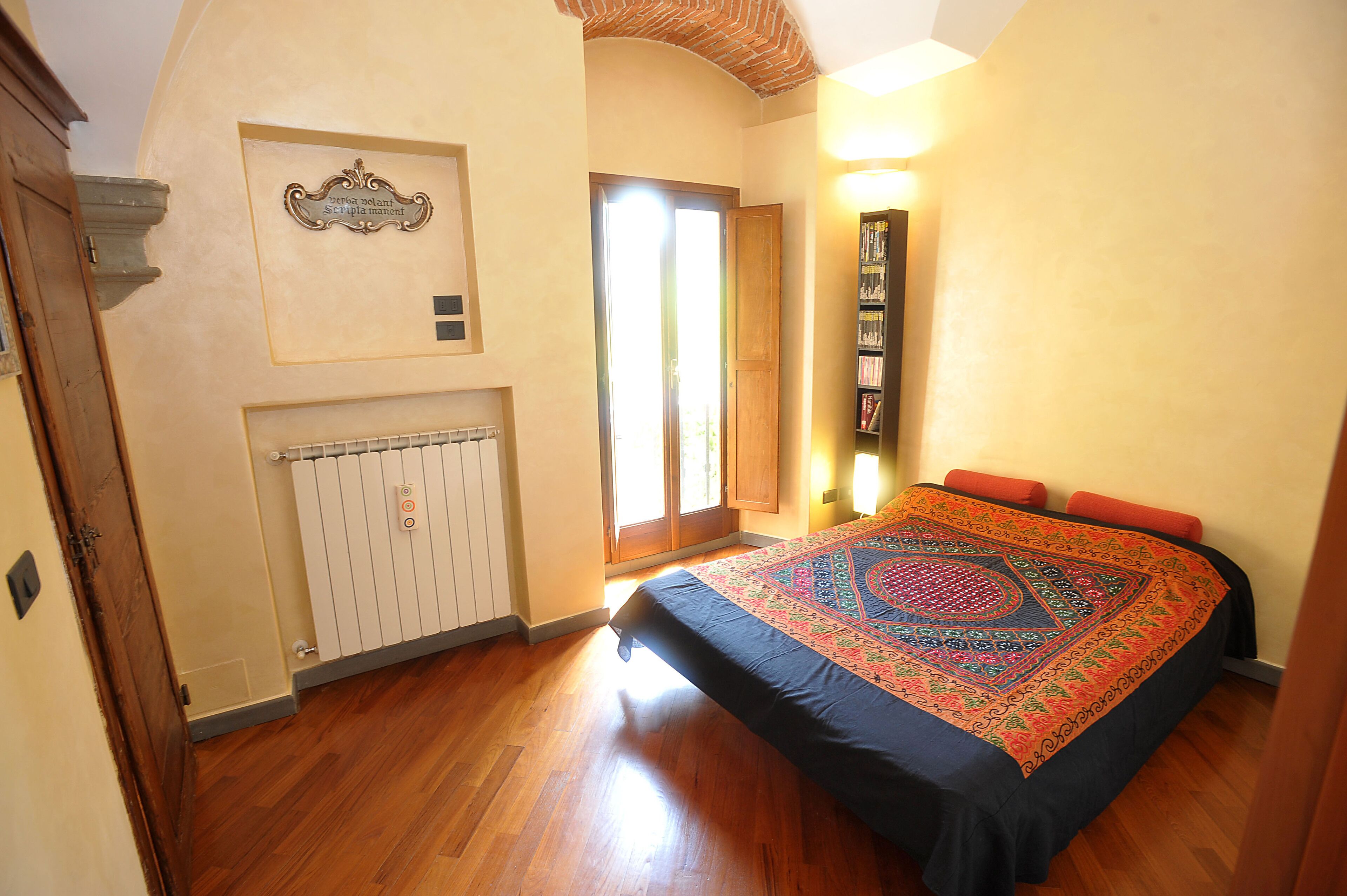 A bedroom with a bed, radiator, and a bookshelf.