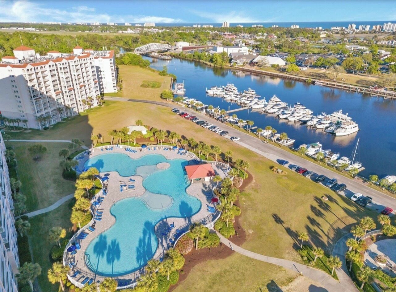Un complexe hôtelier doté d’une grande piscine, d’un port de plaisance avec des bateaux et d’un bâtiment principal.