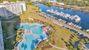 A resort with a large swimming pool, marina with boats, and a hotel building.