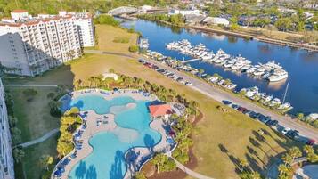 Un complexe hôtelier doté d’une grande piscine, d’un port de plaisance avec des bateaux et d’un bâtiment principal.