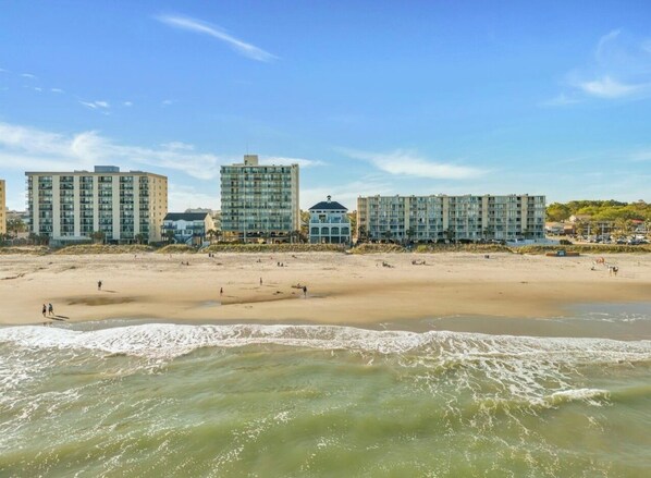 A beachfront hotel with multiple buildings, sandy beach, and ocean waves.