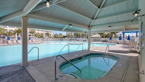 A covered swimming pool with multiple lanes, a diving board, and lounge chairs.