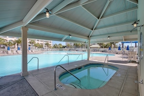 A covered swimming pool with multiple lanes, a diving board, and lounge chairs.