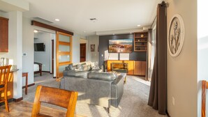 A modern living room with a grey sofa, wooden coffee table, and a fireplace. There is a TV mounted on the wall and a painting above it. - Incredible Views of Lake Chelan-Pool, Outdoor Spas (Manson)