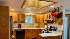 A kitchen with wooden cabinets, a built-in oven, a coffee maker, and a window.