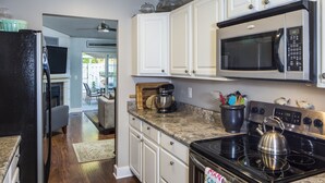 A modern kitchen with white cabinets, a stainless steel stove, and a microwave.
