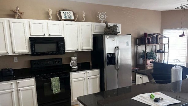 A kitchen with white cabinets, a black stove, a stainless steel refrigerator, and a coffee maker. - DESTIN HARBORWALK BEST LOCATION in DESTIN with Boatdock (destin)