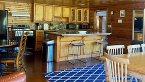 Una cocina amplia con armarios de madera, una isla central y taburetes de bar.
