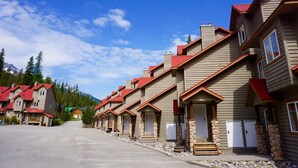 Une rangée de bâtiments de style chalet, avec des toits rouges, des piliers en pierre et un ciel dégagé.