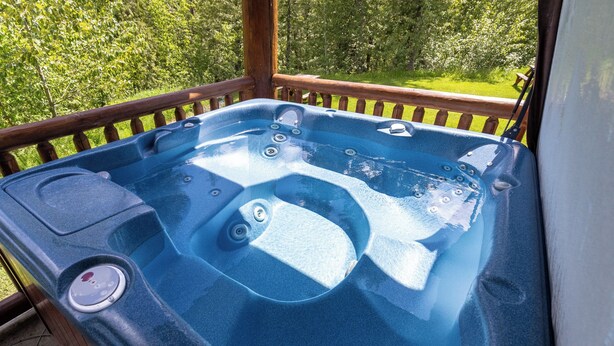 Un bain à remous sur une terrasse en bois, avec vue sur un paysage verdoyant.